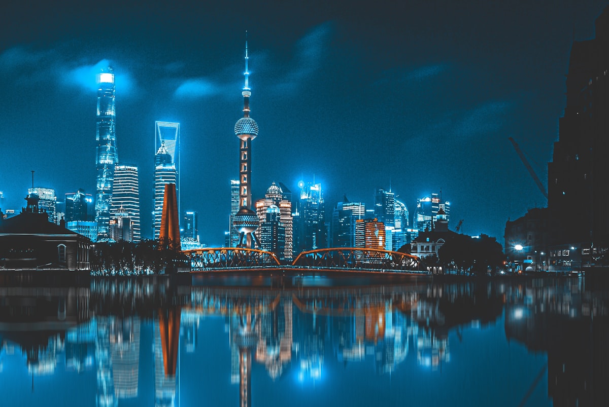 The Shanghai skyline lit up at night reflected in the river