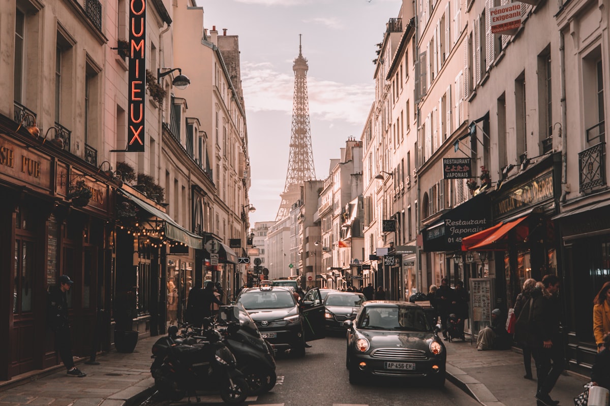 Paris street lined with cafés and the Eiffel Tower framed at the end of the avenue