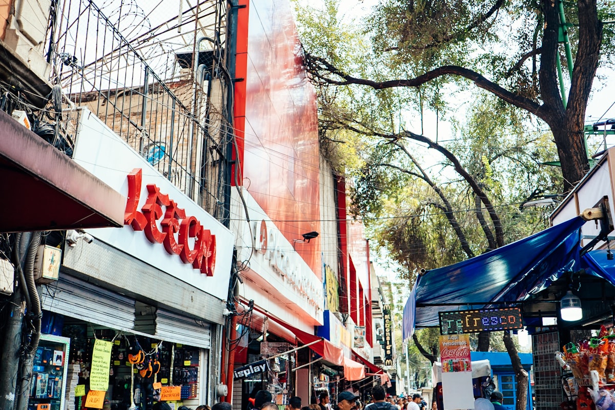 Busy Mexico City street lined with small shops and a market stall