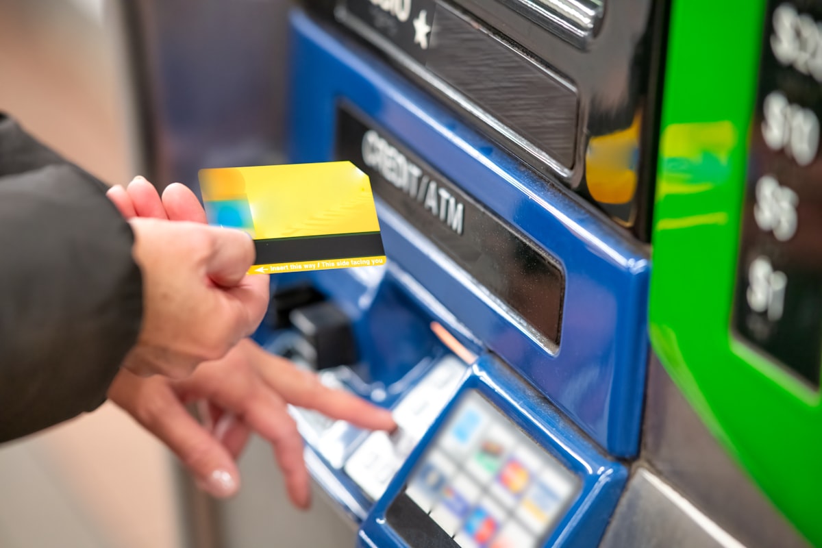 A hand inserting a payment card into the slot of an unattended self-service ticket machine