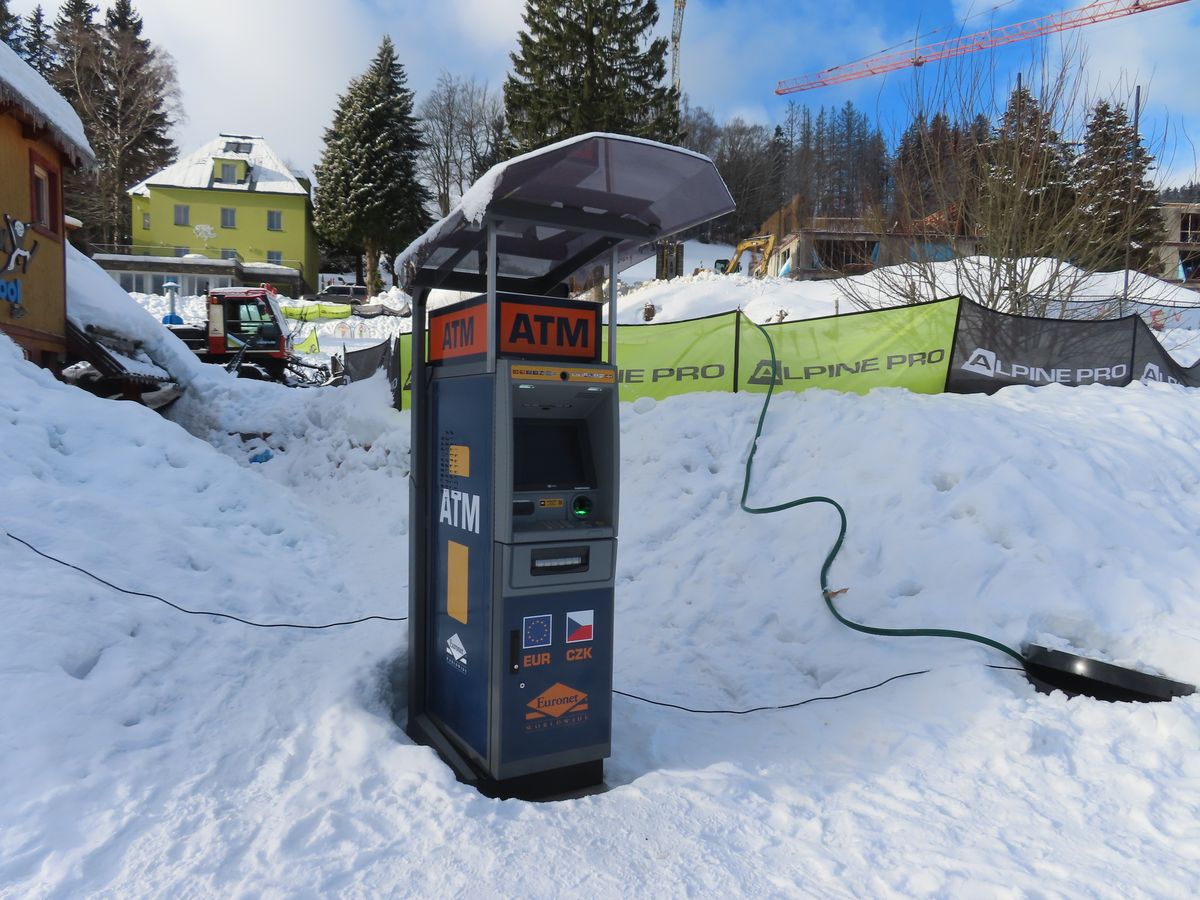 A standalone Euronet ATM under a canopy in a snowy European resort town